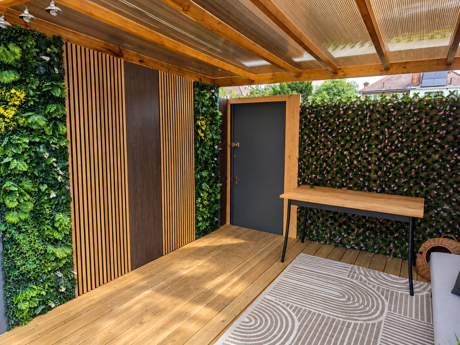 Wide view of the completed outdoor gazebo with timber panels, greenery and front fence
