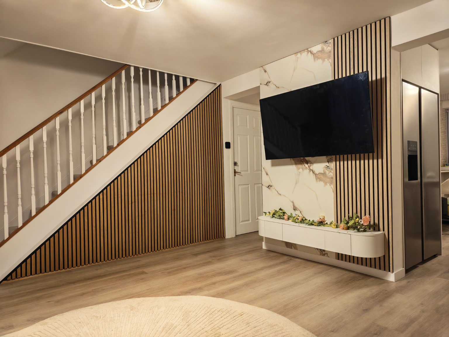 Completed TV wall with marble-effect finish and slatted staircase panelling